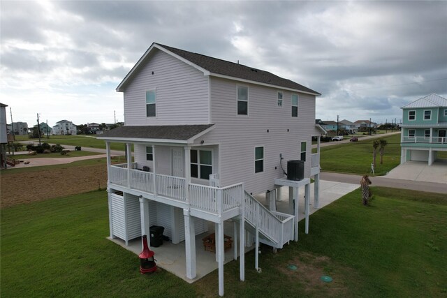 18103 Shaman Dr, Galveston, TX 77554 - back of house featuring a shingled roof, a patio area, a lawn, and a residential view