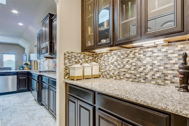 3614 Daintree Park Dr, Katy, TX 77494 - kitchen with stainless steel appliances, dark brown cabinets, vaulted ceiling, tasteful backsplash, and light stone counters