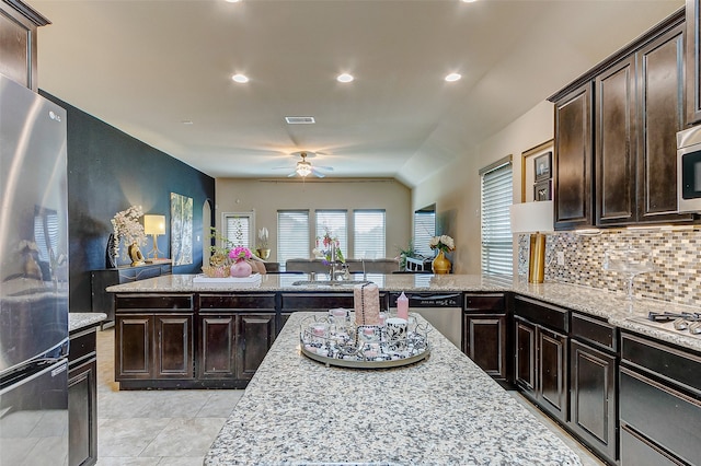 kitchen with kitchen peninsula, dark brown cabinets, light tile patterned flooring, and stainless steel appliances