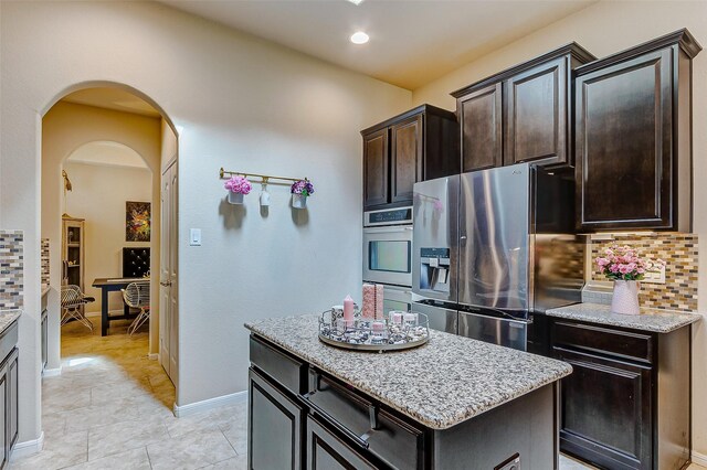 3614 Daintree Park Dr, Katy, TX 77494 - kitchen with appliances with stainless steel finishes, decorative backsplash, light stone countertops, a kitchen island, and recessed lighting