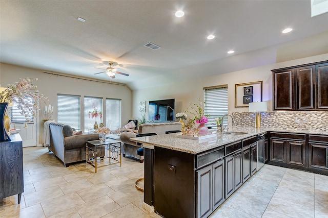 kitchen featuring sink, kitchen peninsula, light stone countertops, stainless steel dishwasher, and decorative backsplash