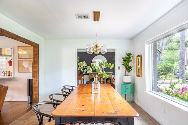 dining room featuring crown molding, tile patterned flooring, a healthy amount of sunlight, and an inviting chandelier