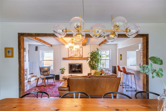 dining area with a chandelier, a brick fireplace, and ornamental molding