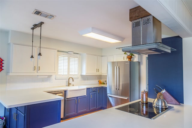 kitchen featuring island range hood, sink, blue cabinetry, decorative light fixtures, and stainless steel refrigerator