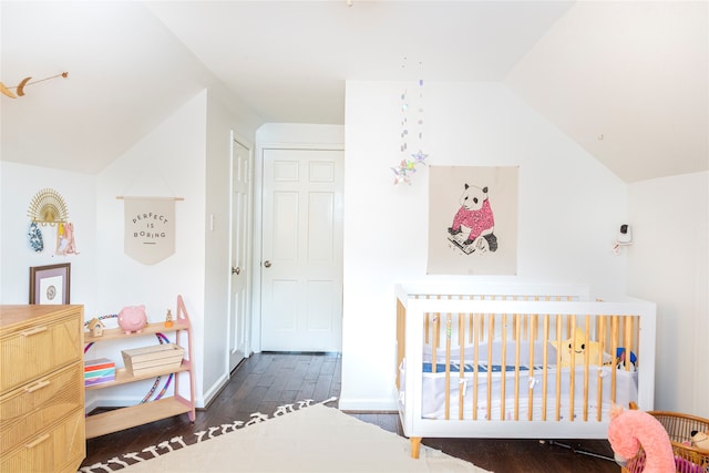 bedroom with dark hardwood / wood-style floors, a crib, and lofted ceiling