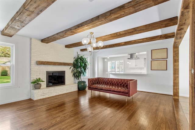 living room with hardwood / wood-style flooring, a fireplace, beamed ceiling, and an inviting chandelier