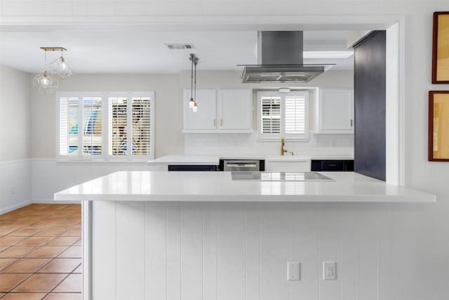 kitchen featuring white cabinets, wall chimney exhaust hood, a healthy amount of sunlight, and decorative backsplash