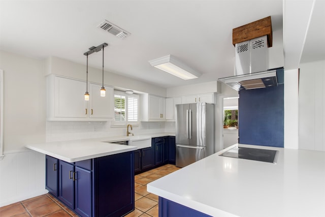 kitchen featuring black electric stovetop, stainless steel fridge, white cabinetry, and blue cabinets