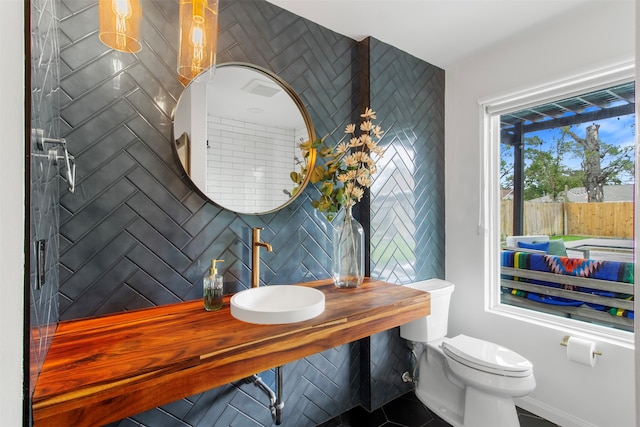 bathroom featuring decorative backsplash, sink, tile patterned flooring, and toilet