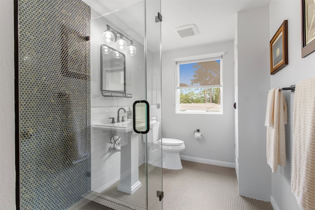 bathroom with tile patterned flooring, a shower with door, and toilet