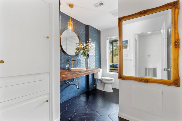 bathroom featuring tile patterned flooring, decorative backsplash, toilet, and sink