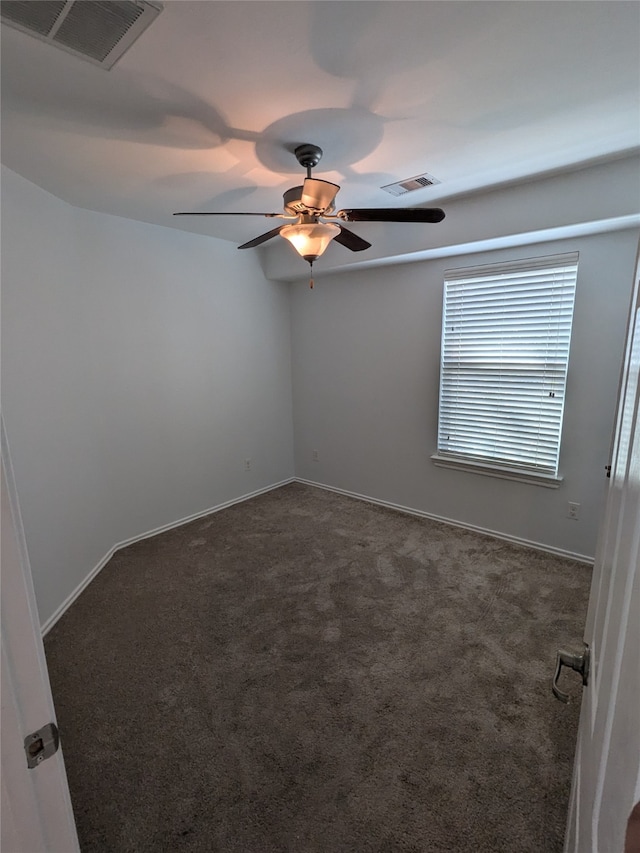 empty room with ceiling fan and dark carpet