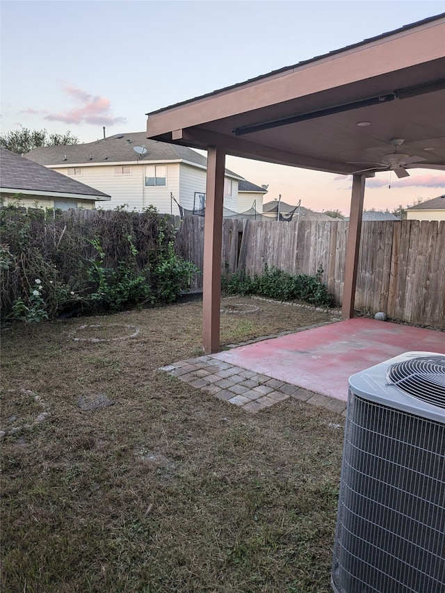 yard at dusk with central AC unit, a patio, and ceiling fan