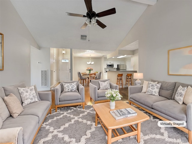 living room featuring ceiling fan with notable chandelier, hardwood / wood-style flooring, and high vaulted ceiling