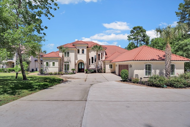 mediterranean / spanish house featuring a garage and a front yard