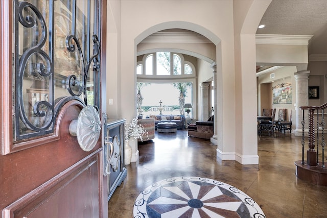 entrance foyer with finished concrete flooring, decorative columns, ornamental molding, and baseboards