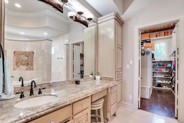 bathroom featuring tiled shower, vanity, tile patterned flooring, and ornamental molding