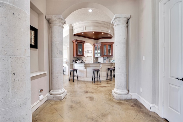 hall with light tile patterned floors and decorative columns