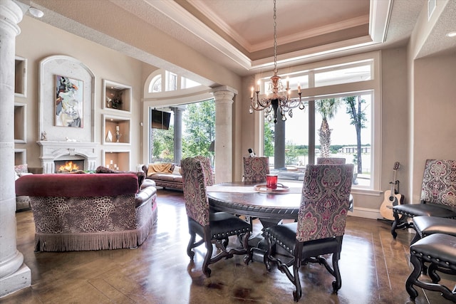 dining room with an inviting chandelier, decorative columns, ornamental molding, a raised ceiling, and built in features