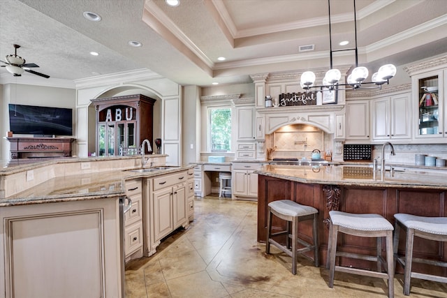 kitchen featuring tasteful backsplash, light stone counters, a textured ceiling, and a large island with sink