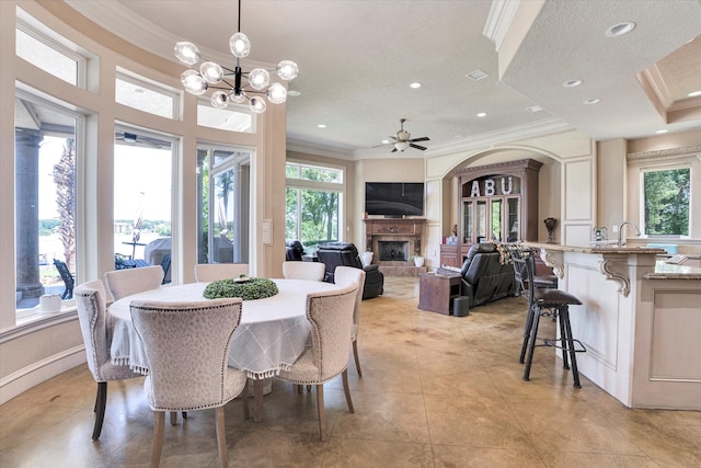 tiled dining area featuring a fireplace, plenty of natural light, and crown molding