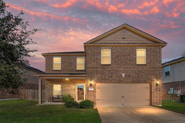 traditional home with an attached garage, brick siding, fence, a yard, and concrete driveway