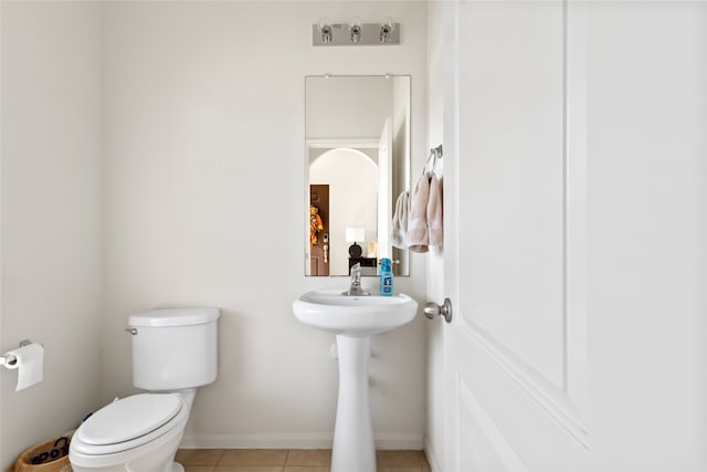 half bath featuring toilet, baseboards, and tile patterned floors