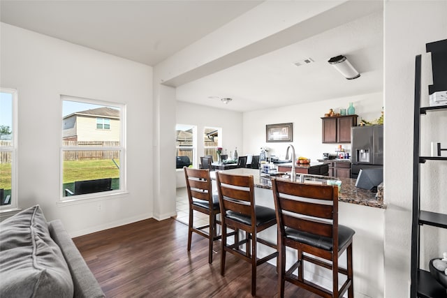 dining space with dark wood-style flooring, visible vents, and baseboards