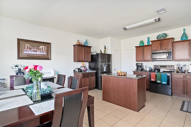 kitchen featuring a center island, light tile patterned floors, visible vents, appliances with stainless steel finishes, and dark stone countertops