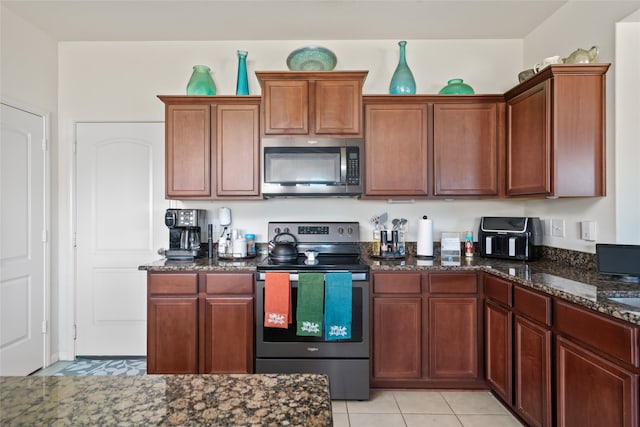 kitchen featuring dark stone counters, appliances with stainless steel finishes, and light tile patterned floors