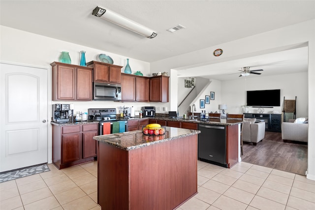 kitchen with a peninsula, open floor plan, appliances with stainless steel finishes, a center island, and dark stone countertops