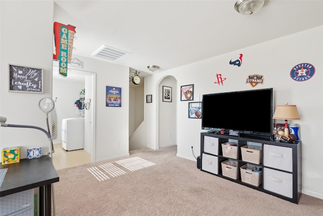 living room with light colored carpet, washer / clothes dryer, visible vents, and arched walkways