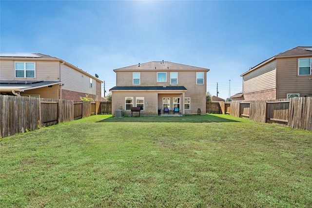 rear view of house featuring central AC, a lawn, and a fenced backyard