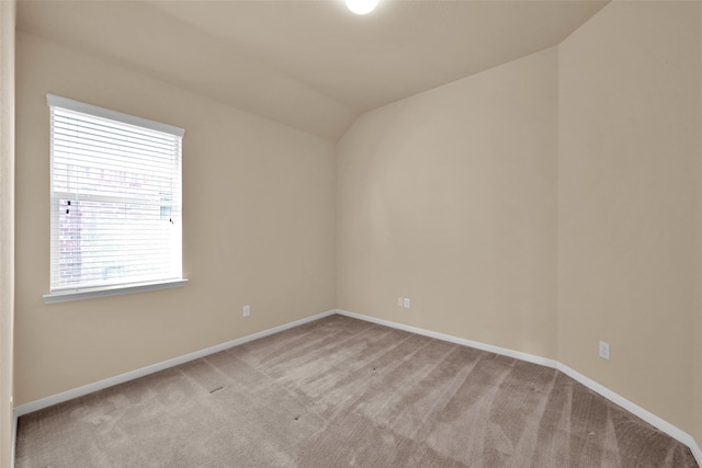 unfurnished room with vaulted ceiling and light carpet