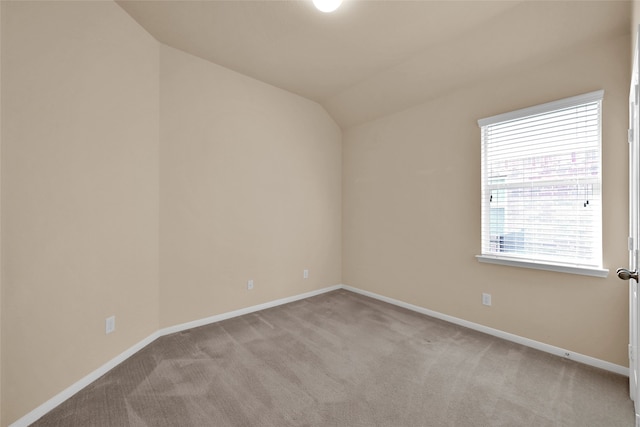 carpeted empty room featuring vaulted ceiling