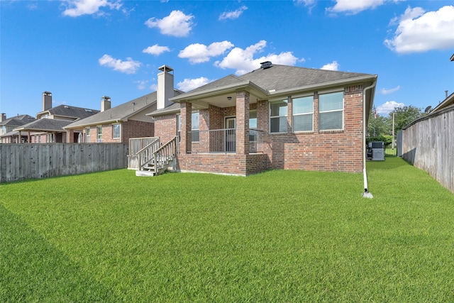 rear view of house with central AC unit and a yard