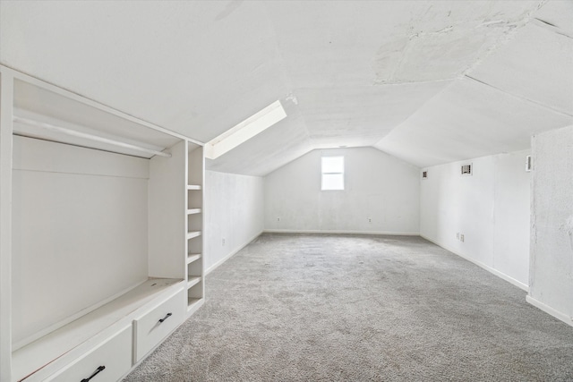 additional living space featuring lofted ceiling with skylight and carpet