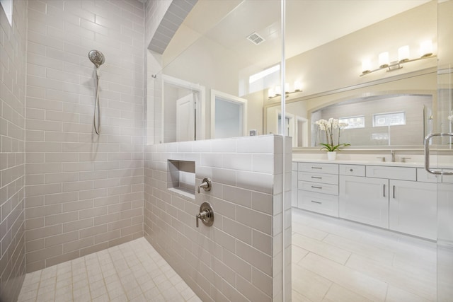 bathroom featuring tiled shower, tile walls, vanity, and tile patterned floors