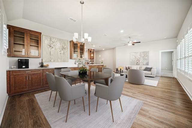 dining area with ceiling fan with notable chandelier and light hardwood / wood-style flooring