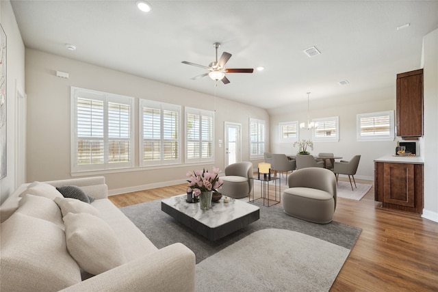 living room featuring hardwood / wood-style floors, ceiling fan with notable chandelier, and a healthy amount of sunlight