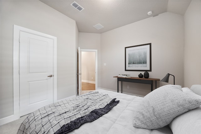 carpeted bedroom featuring a textured ceiling and vaulted ceiling