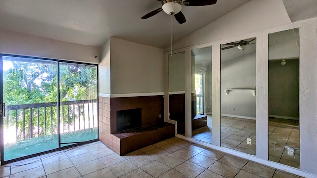 unfurnished living room with ceiling fan, a tile fireplace, light tile patterned floors, and vaulted ceiling