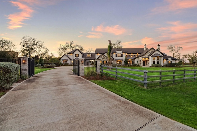 exterior space featuring a fenced front yard, stone siding, a lawn, a gate, and a chimney