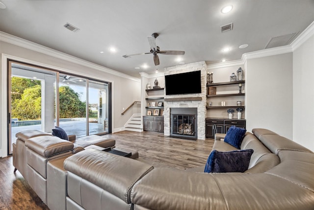 living area featuring visible vents, ceiling fan, wood finished floors, crown molding, and a fireplace