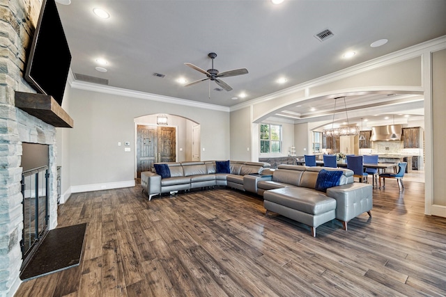 living room featuring a fireplace, visible vents, arched walkways, and wood finished floors