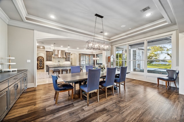 dining area with dark hardwood / wood-style floors, an inviting chandelier, ornamental molding, and a tray ceiling