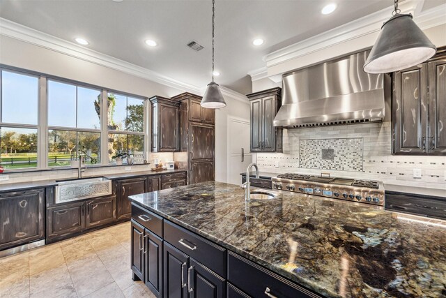 kitchen featuring wall chimney exhaust hood, crown molding, dark brown cabinetry, and hanging light fixtures