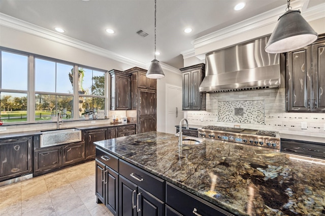 kitchen with wall chimney exhaust hood, hanging light fixtures, a sink, and dark brown cabinetry