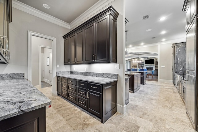 kitchen with arched walkways, light stone counters, baseboards, dark brown cabinets, and ornamental molding