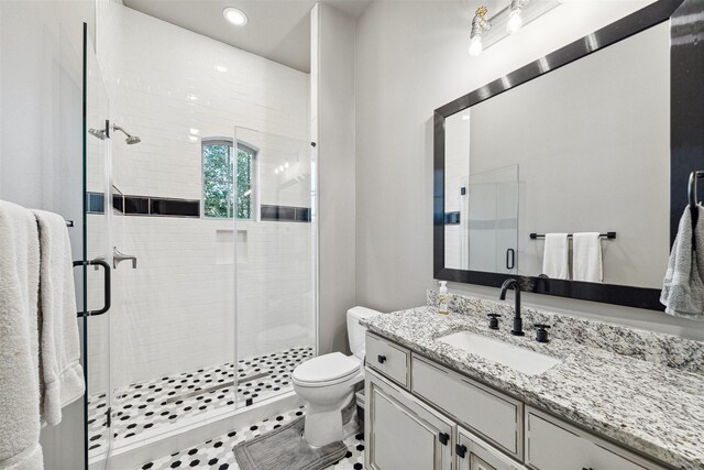 bathroom with tile patterned flooring, vanity, toilet, and walk in shower